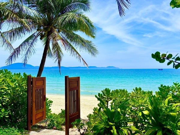 Bãi biển xanh trong tại Pax Ana Dốc Lết Resort & Spa, Khánh Hòa với lối đi ra biển thơ mộng giữa hàng dừa xanh mát.